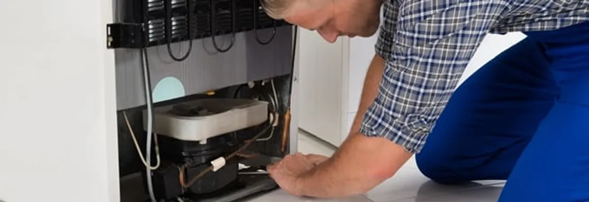 Refrigerator repair technician servicing the compressor and condenser area in Scottsdale, AZ