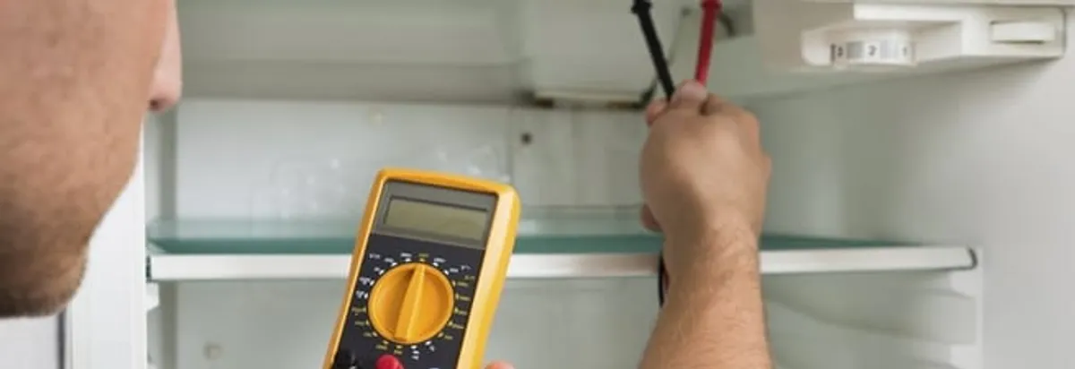 Refrigerator repair technician testing electrical components with a multimeter in Scottsdale, AZ